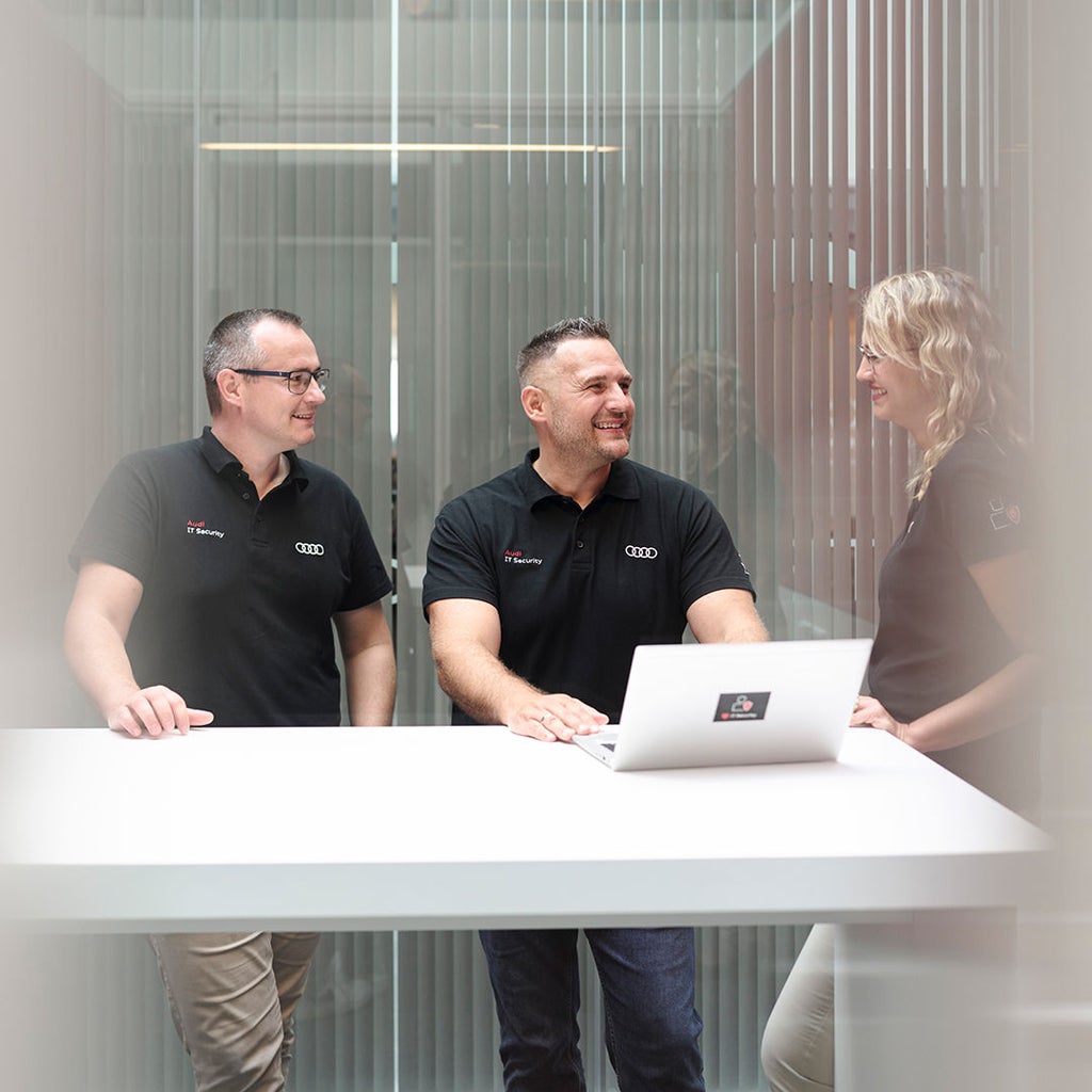 Andreas Walter spricht mit Kollegen und hat einen Laptop vor sich