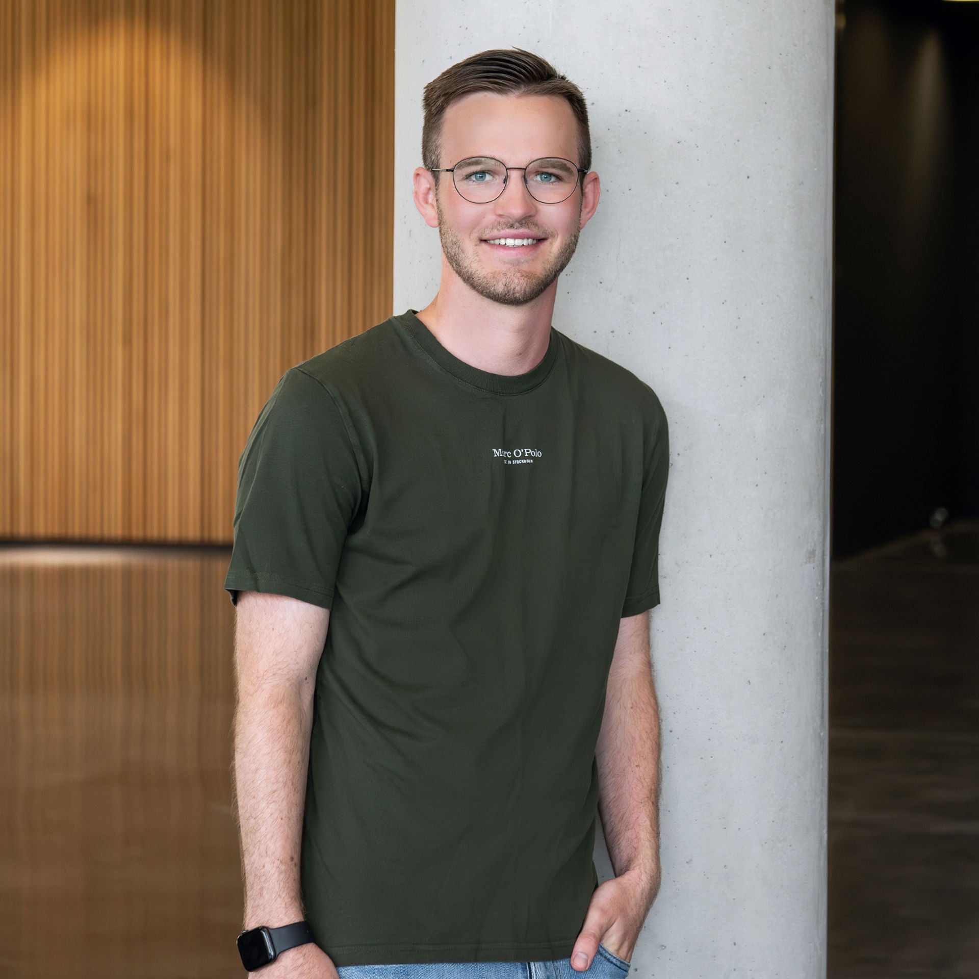 Jonas Kufer smiles at the camera, leaning against a concrete pillar