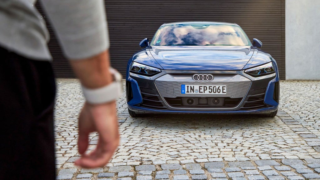 Un homme porte une montre connectée devant Audi.