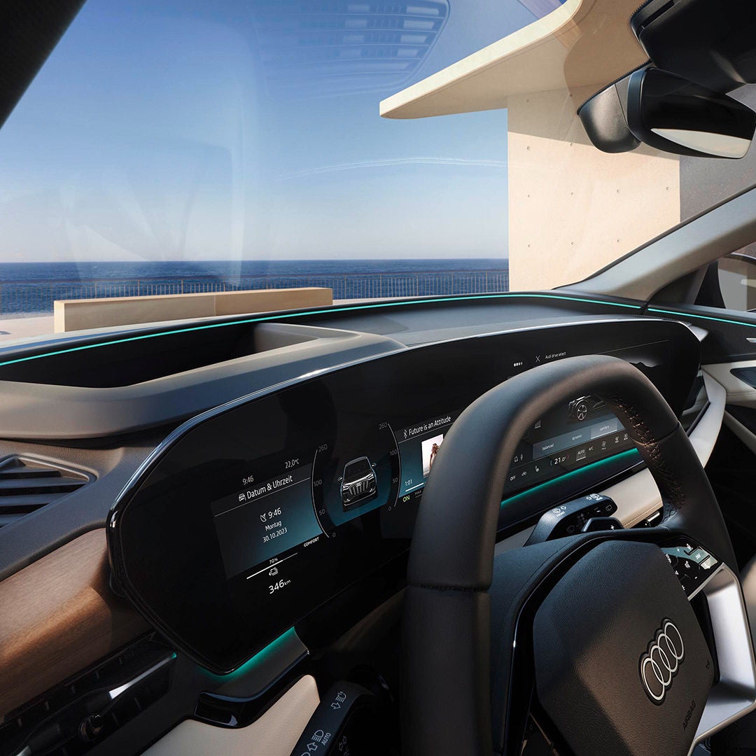 Digitales Cockpit eines Audi mit breitem Display und Blick auf das Meer durch die Windschutzscheibe.