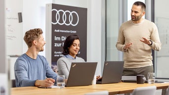 Eine Frau und ein Mann stehen hinter einem Audi Q5 Modell