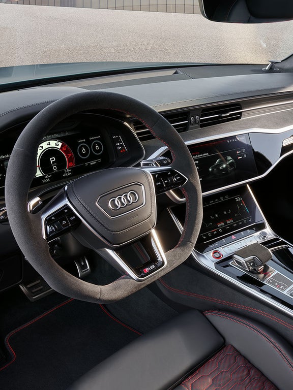 Blick ins Cockpit eines Audi RS 6 Avant performance mit Alcantara-Lenkrad, Digitalanzeigen, Touchscreen und roter Ziernaht.