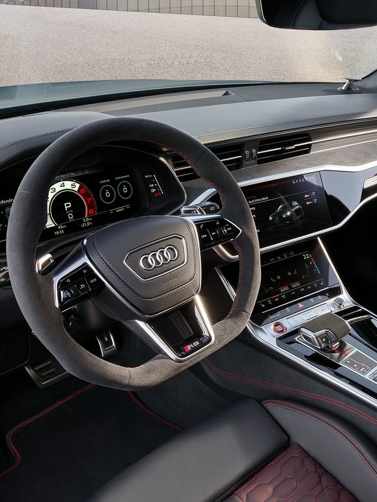 Blick ins Cockpit eines Audi RS 6 Avant performance mit Alcantara-Lenkrad, Digitalanzeigen, Touchscreen und roter Ziernaht.