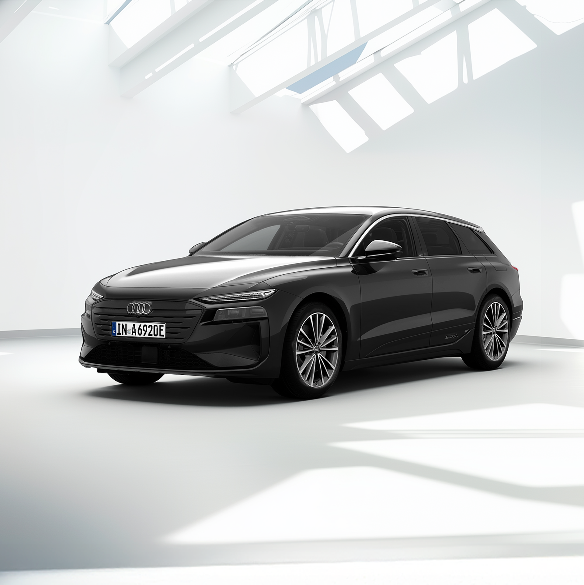 Grauer Audi A6 Avant e-tron steht vor einem modernen Gebäude bei Sonnenuntergang.