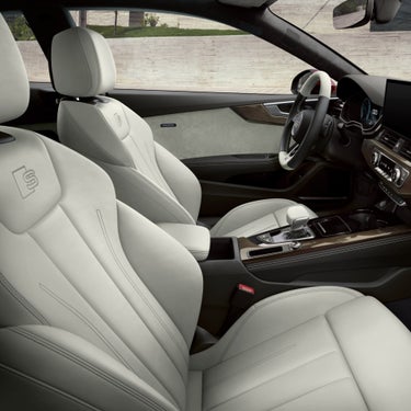 Car's interior with cream leather seats, steering wheel, and dashboard.