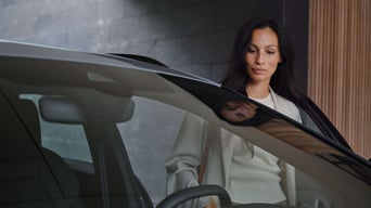 Eine Frau steigt in einen Audi im Hintergrund ist eine Betonwand.