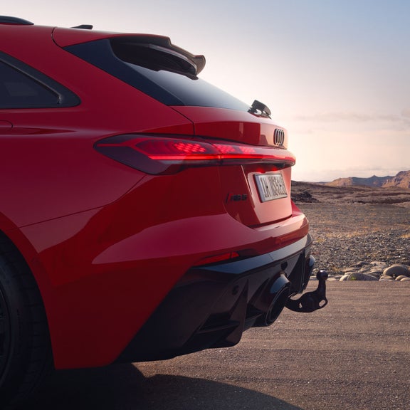 Side view of the RS 5 Avant with focus on the rear and the trailer coupling, with a rocky landscape in the background.
