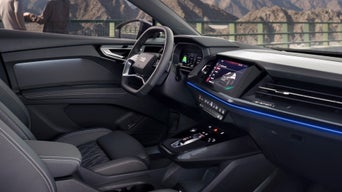 Interior view of an Audi vehicle featuring a digital dashboard, luxurious seats, and ambient lighting.