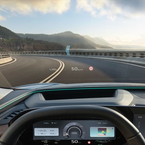 The Q6 SUV e-tron from the driver's perspective while driving. The head-up display shows the speed, speed limit, navigation information, and the path of the next curve.