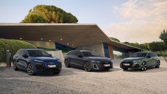 3 junge Audi Gebrauchtwagen vor moderner Architektur in sommerlichem Ambiente.