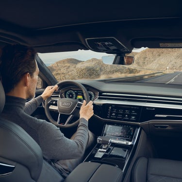 Person driving an Audi with desert landscape visible through the windshield.
