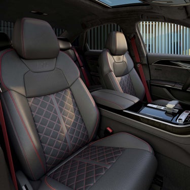 Innenraum mit schwarzen Sportsitzen, roten Nähten und Panoramadach im Audi S8 TFSI, Blick auf vordere Sitzreihe und Mittelkonsole.