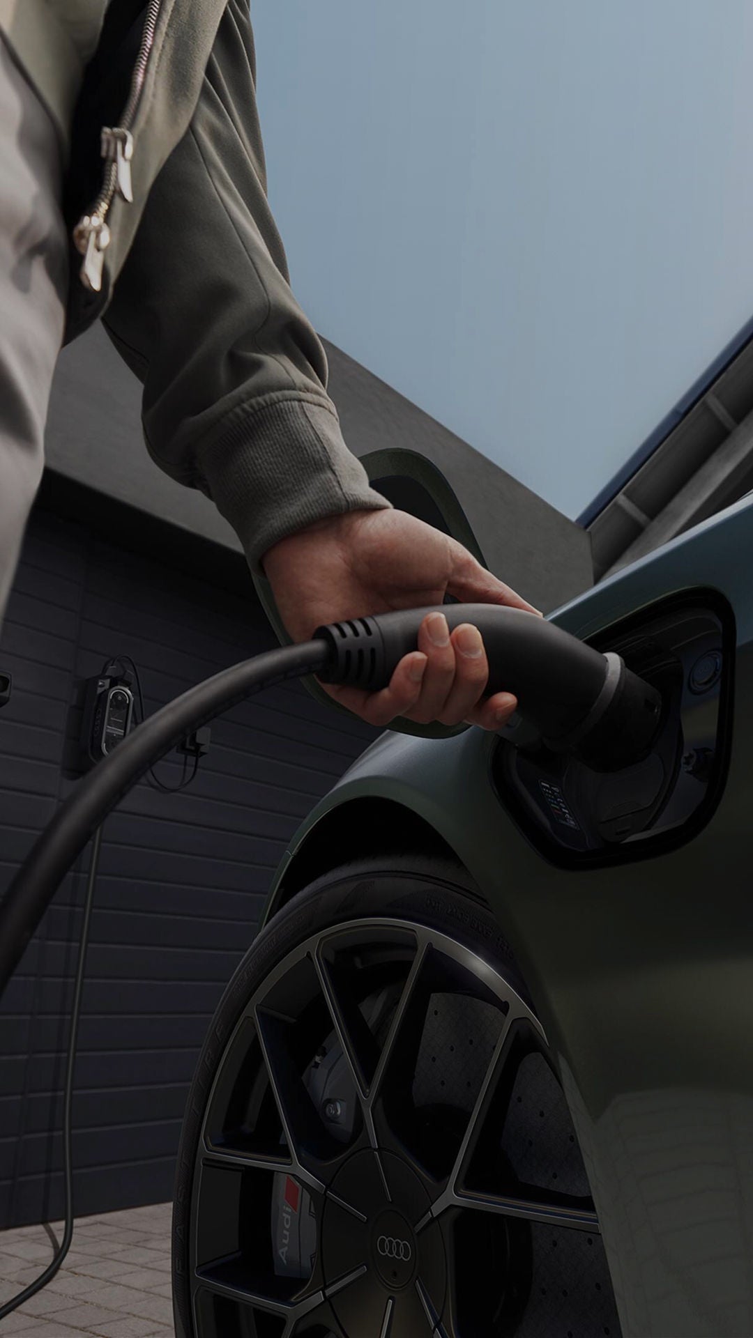 A person charges a sleek electric car using a charging cable. The focus is on the hand and cable, conveying eco-friendly and modern technology themes.
