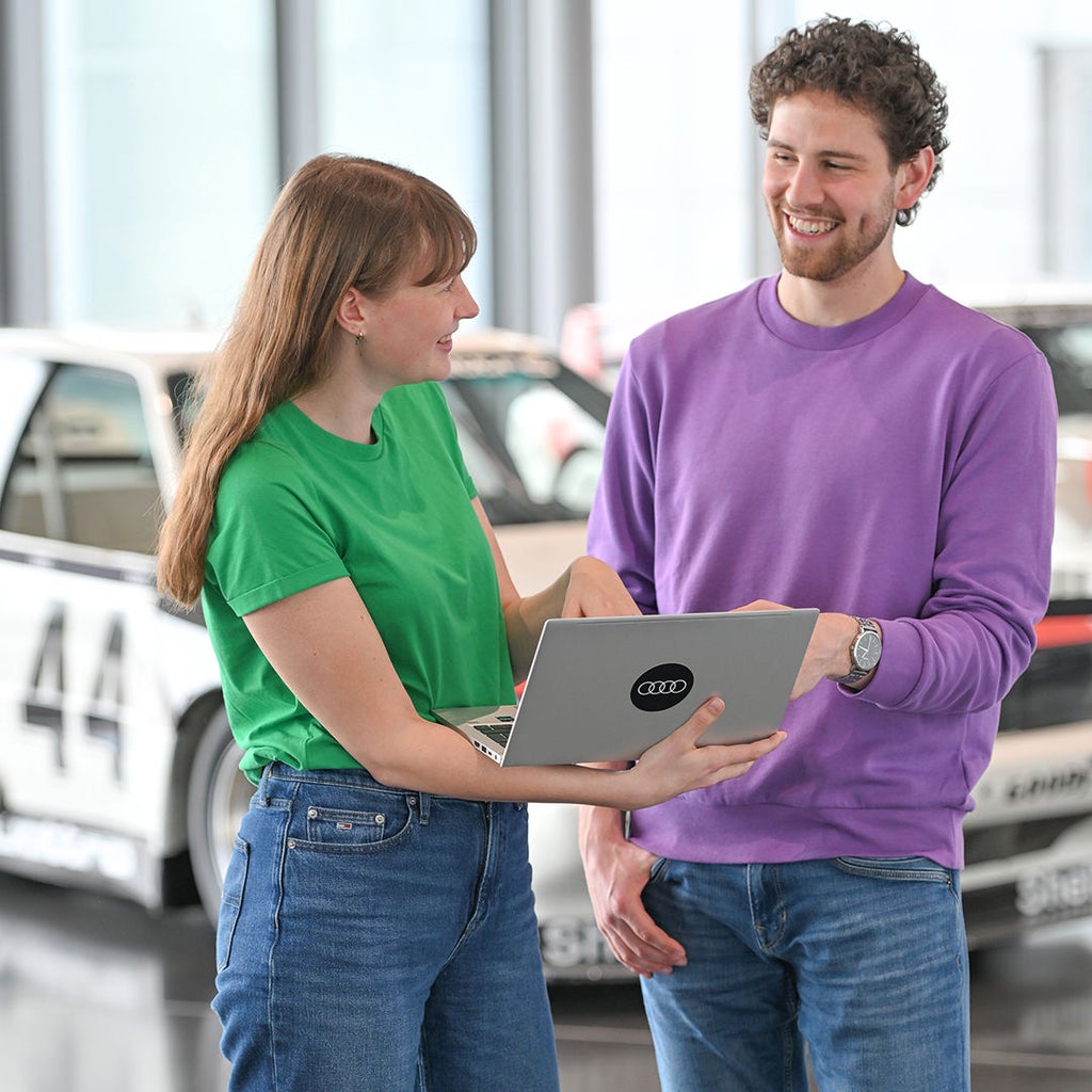 Fabian spricht mit einer Kollegin die einen Laptop in der Hand hat