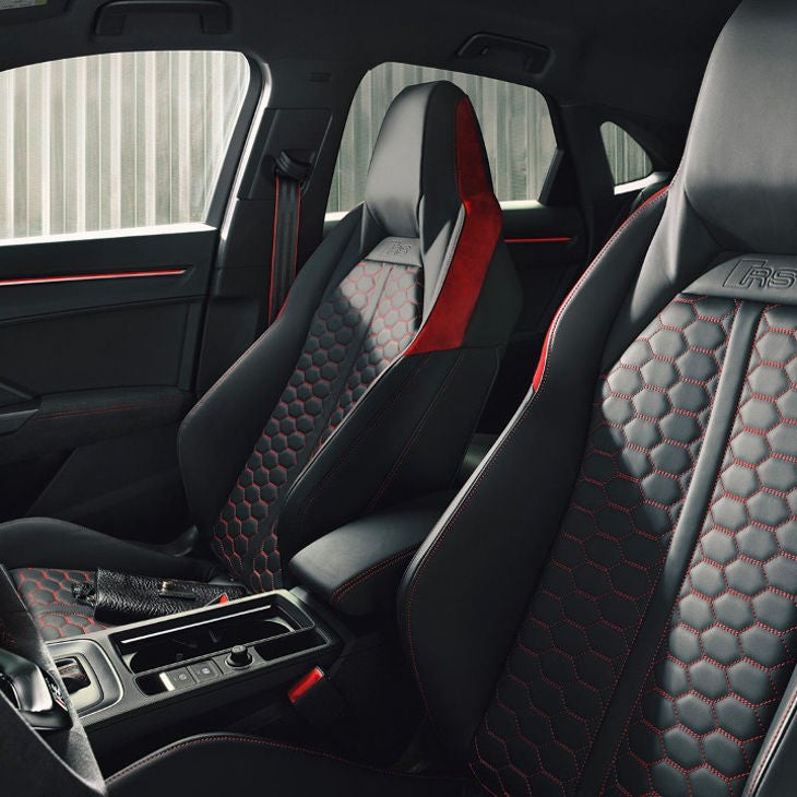 Car interior with black and red leather sport seats and stylish dashboard.