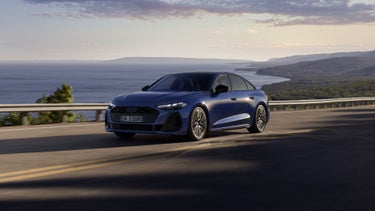 Die S5 Limousine in dunkelblau fährt auf einer Straße entlang der Küste.