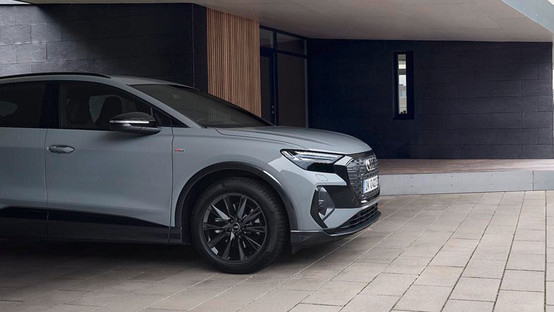 A grey Audi parked on a modern stone-paved patio, featuring a stylish exterior and set against a minimalistic background.