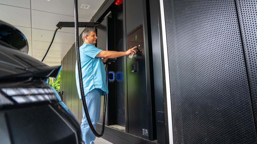A man stands at the charging station in his black Porsche and makes adjustments