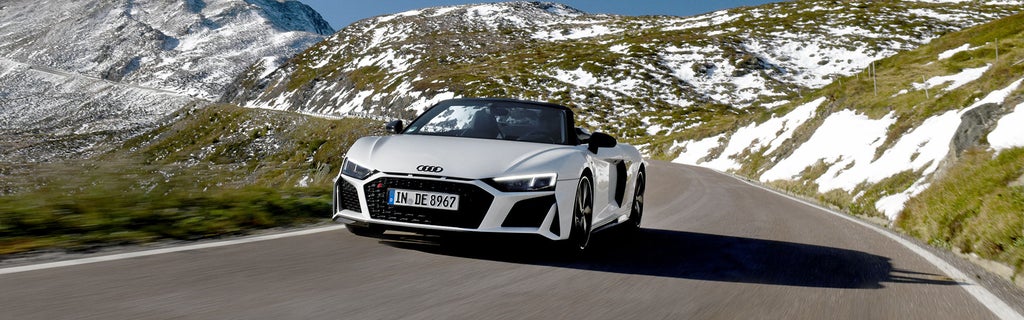 White Audi R8 Spyder drives through the Alps