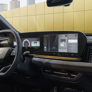 Das Cockpit und Panorama-Display aus Perspektive des Beifahrers. Der Innenraum erscheint in Sonnengelbem Ambiente Licht.