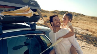 Far bærer datter på ryggen som henter leke fra Audi takboks