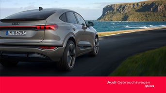 Audi Q6 Sportback e-tron in der Heckansicht auf einer Küstenstraße.