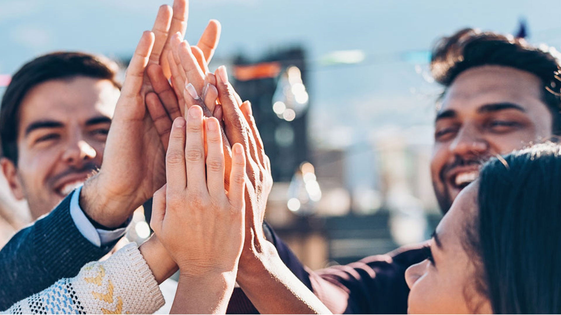 Several people laugh and hold their hands in the centre