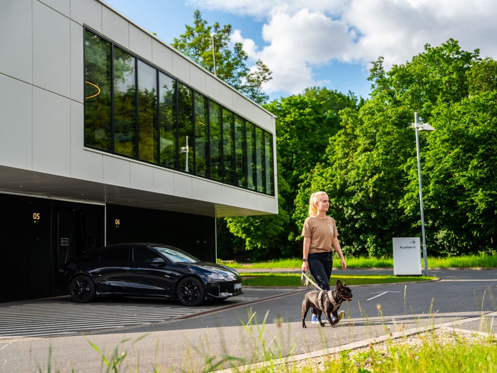 A woman walks away from the Charging hub with her dog on a lead