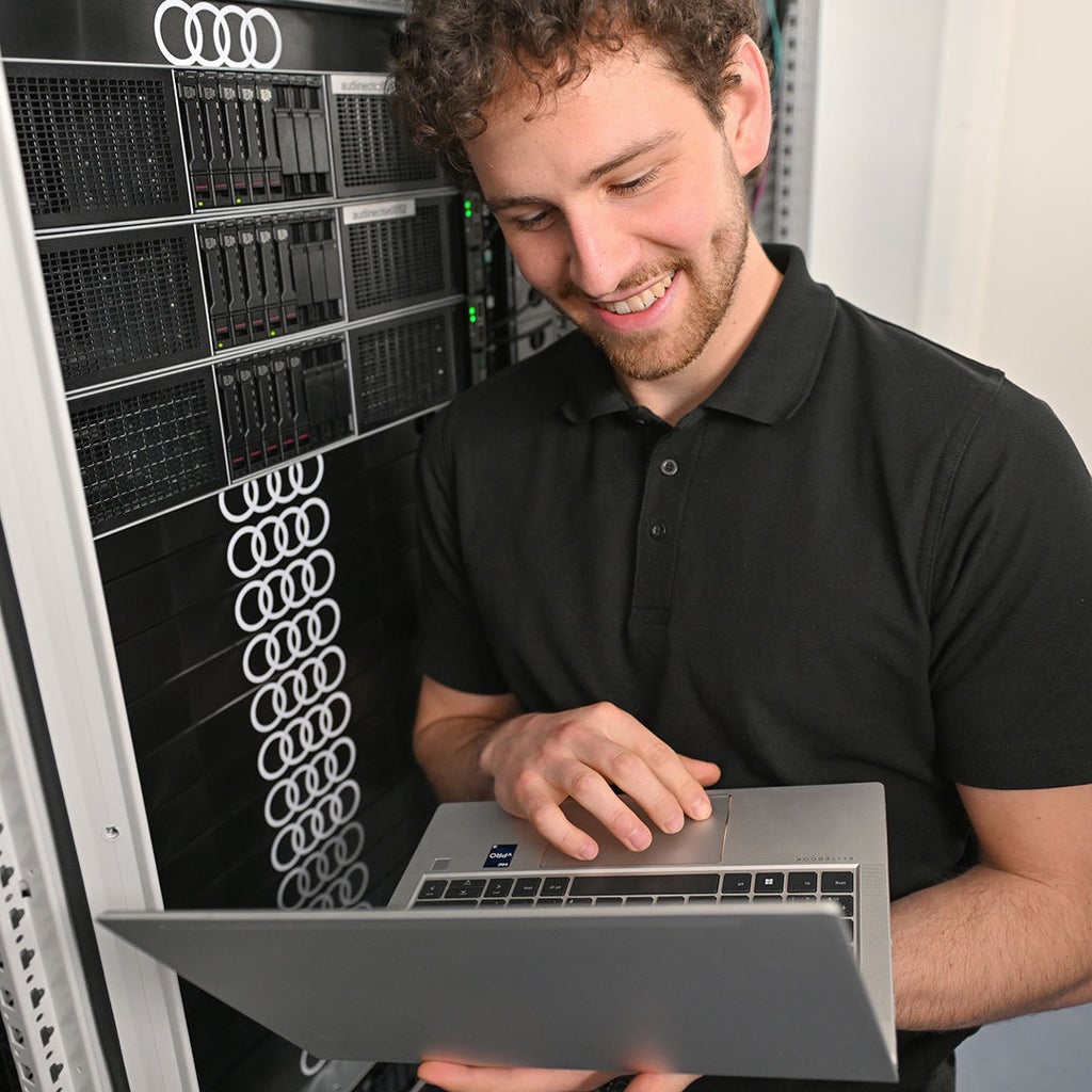 Fabian schaut auf seinen Laptop, den er in der Hand hat
