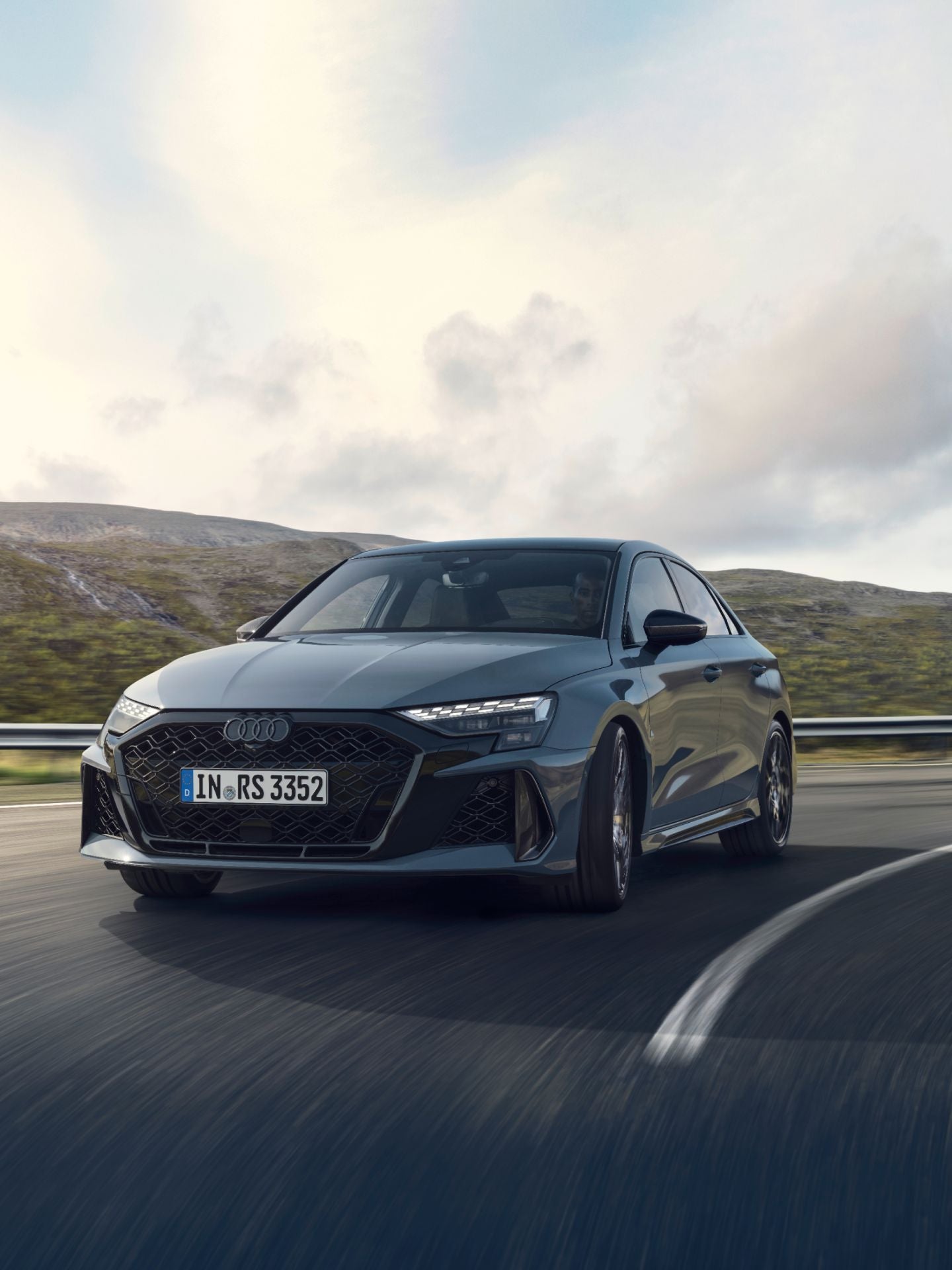 Audi RS3 driving on a highway with mountains in the background.
