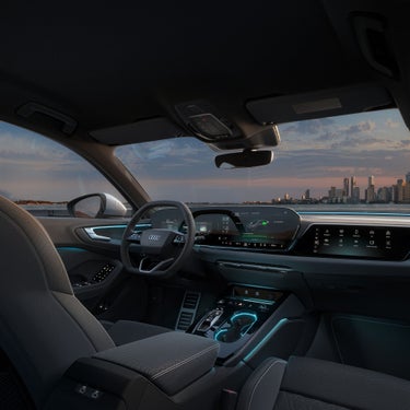 Car interior with a sleek design, featuring illuminated controls, a digital dashboard, and a scenic city skyline visible through the windshield at sunset.