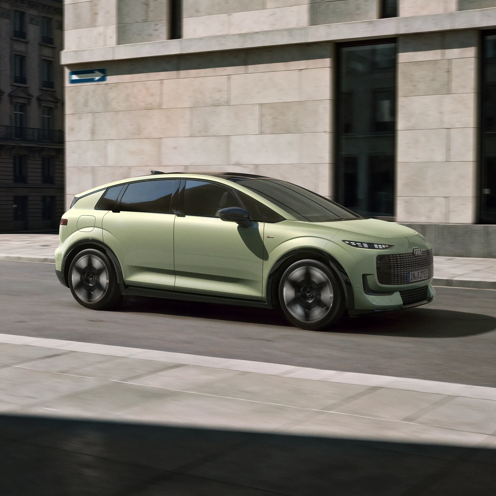 Pistachio green Audi A2 e-tron electric hatchback driving past urban architecture