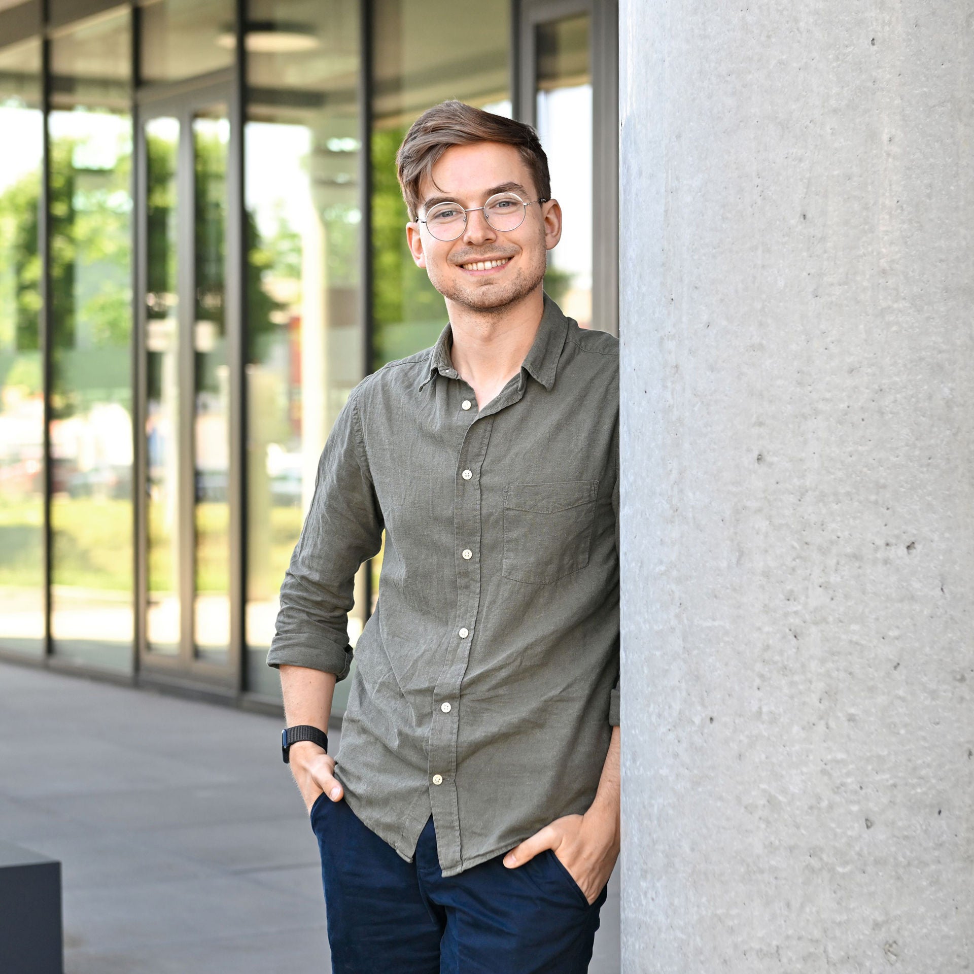 David, Software Engineer SDC, lehnt gegen eine Wand und schaut in die Kamera