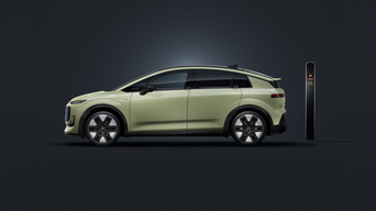 L'Audi A2 e-tron, vue de profil sur un fond sombre, avec une borne de recharge en arrière-plan.