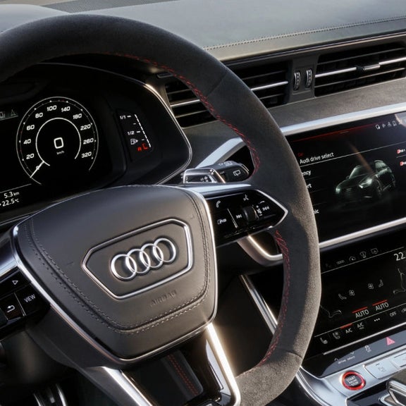 Interior view of an Audi vehicle focusing on the steering wheel and dashboard displays.