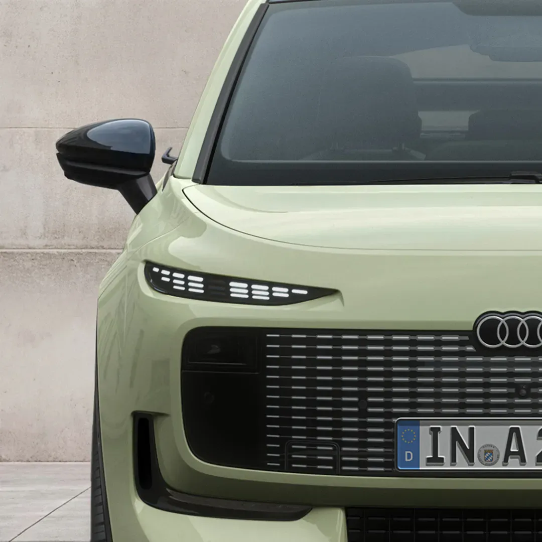 Front view of a light green Audi A2 e-tron electric hatchback showing digital headlights and uniquely styled single-frame grille