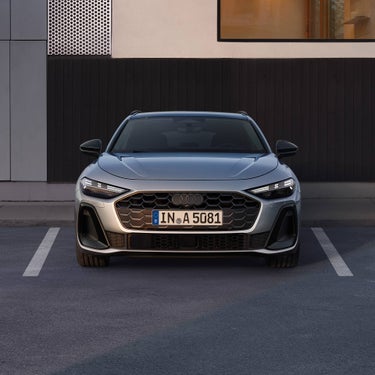 Frontansicht eines silbernen Audi A5 Avant mit LED-Scheinwerfern und deutschem Kennzeichen vor dunkler Wand.