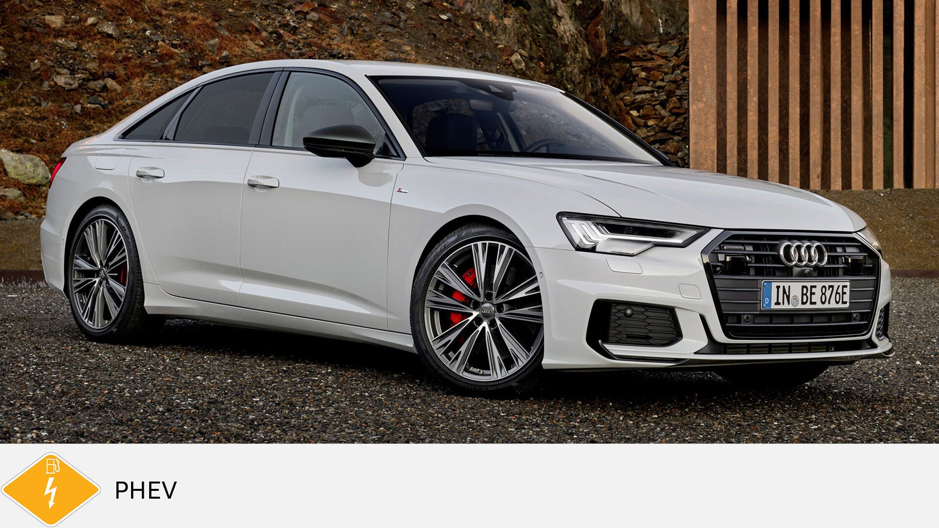 Weißer Audi A6 TFSI e steht auf Kies vor Felswand, leicht von vorne. Unten gelbes PHEV-Symbol mit Zapfsäule.