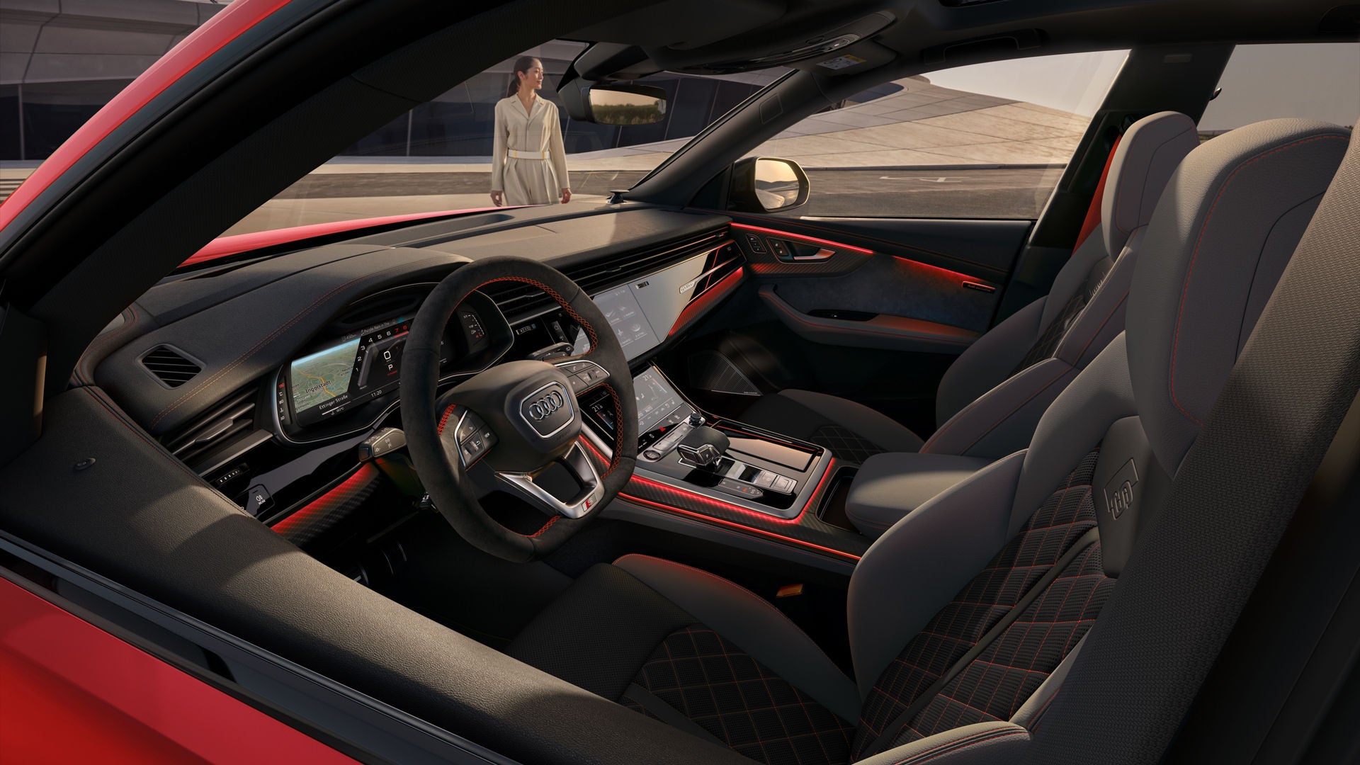 Blik in de cockpit van de SQ8 SUV met het zwart-neodymium gouden designpakket vanaf de bestuurderszijde, met een futuristisch gebouw met een gebogen vorm op de achtergrond.  Voor het voertuig staat een modieus geklede jonge vrouw.