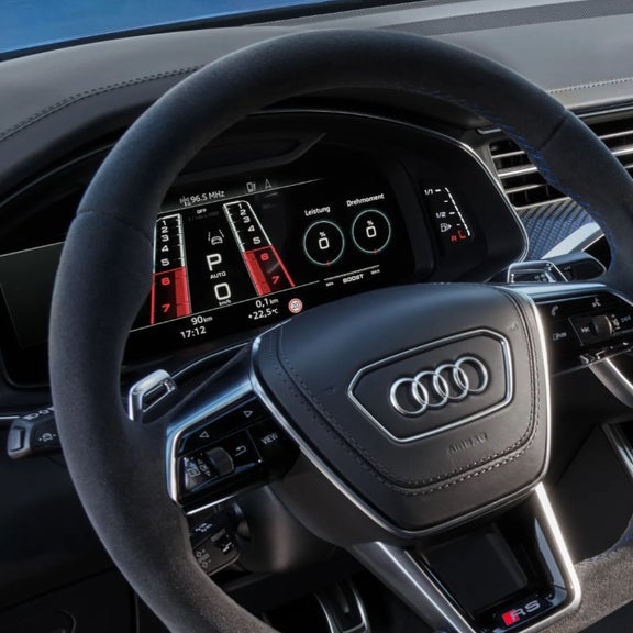 Car interior showing the steering wheel and digital dashboard of an Audi vehicle.