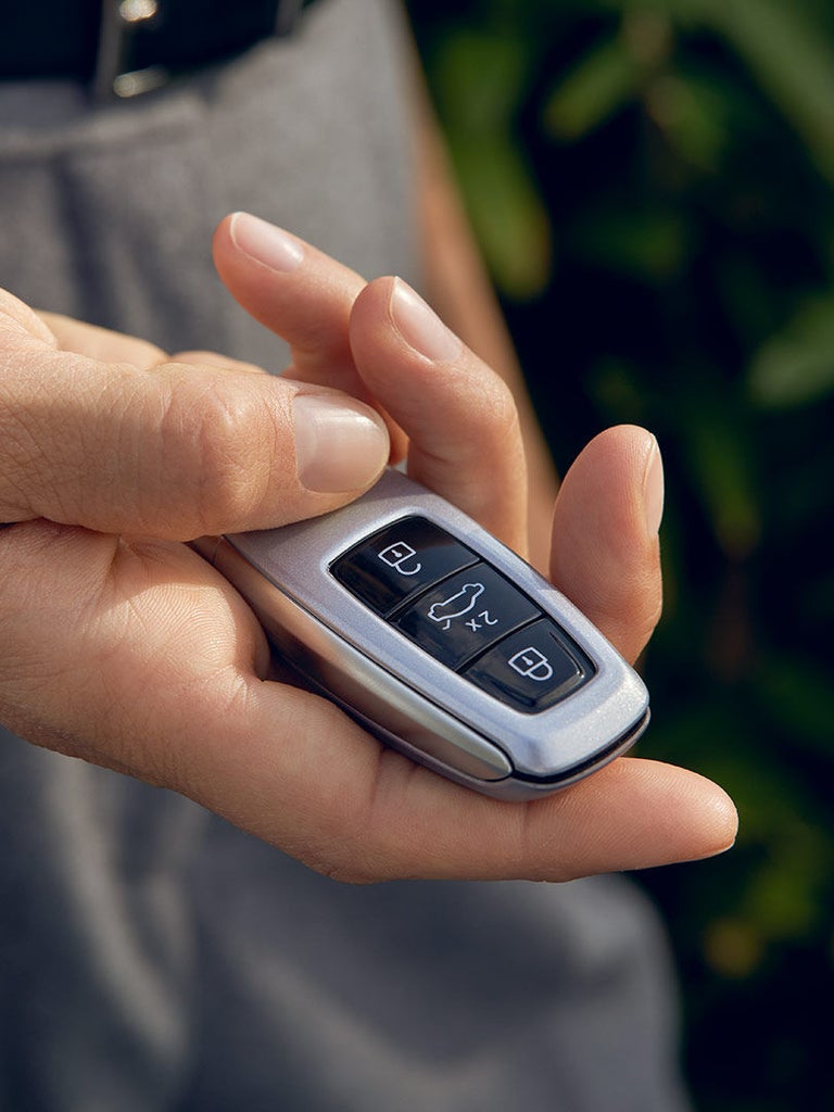 Hand hält einen silbernen Audi-Autoschlüssel mit sichtbaren Bedientasten.
