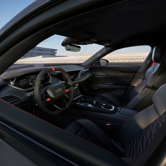 Innenraum eines Audi RS e-tron GT mit schwarzem Alcantara-Lenkrad, roten Nähten und digitalen Displays.