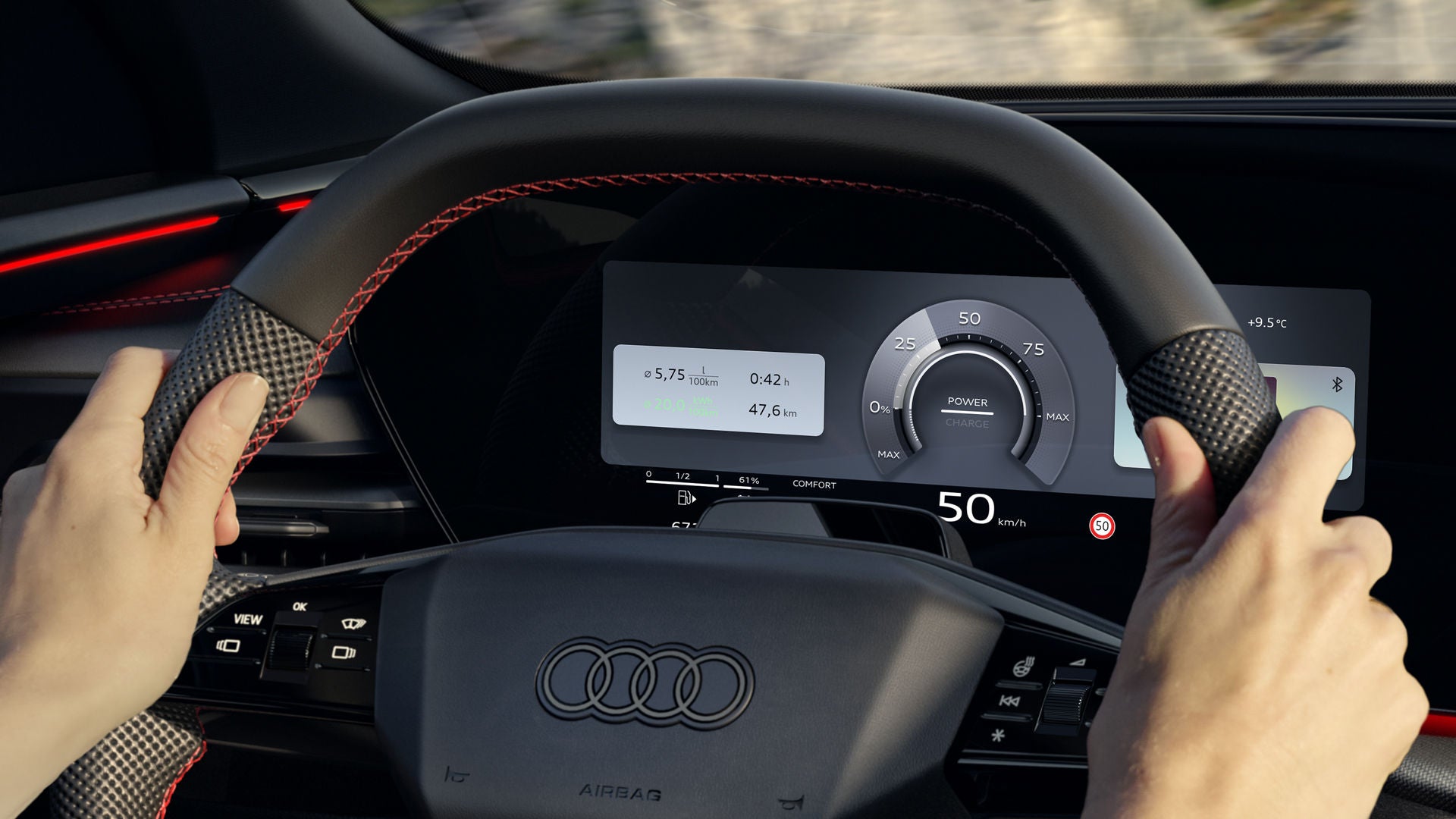 View from the rear seat into the cockpit of the Q5 SUV e-hybrid. A woman is sitting at the wheel, driving along a mountain road. The Audi virtual cockpit plus can be seen behind the steering wheel.