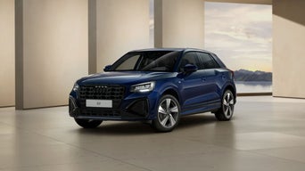 Une Audi Q2 bleu foncé est exposée dans une sorte de salle d'exposition.