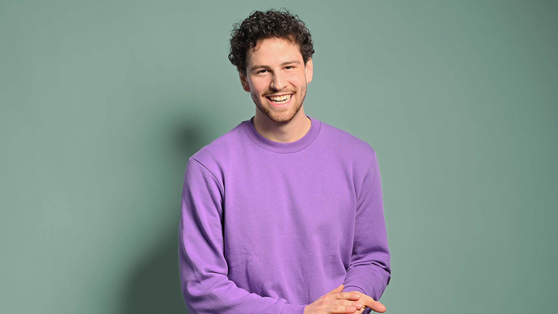 Fabian lacht in die Kamera und hat dabei die Hände gefaltet