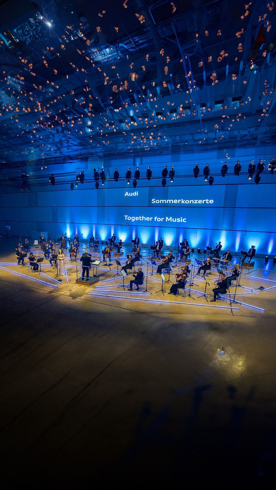 Orchester performt auf einer blau beleuchteten Bühne.