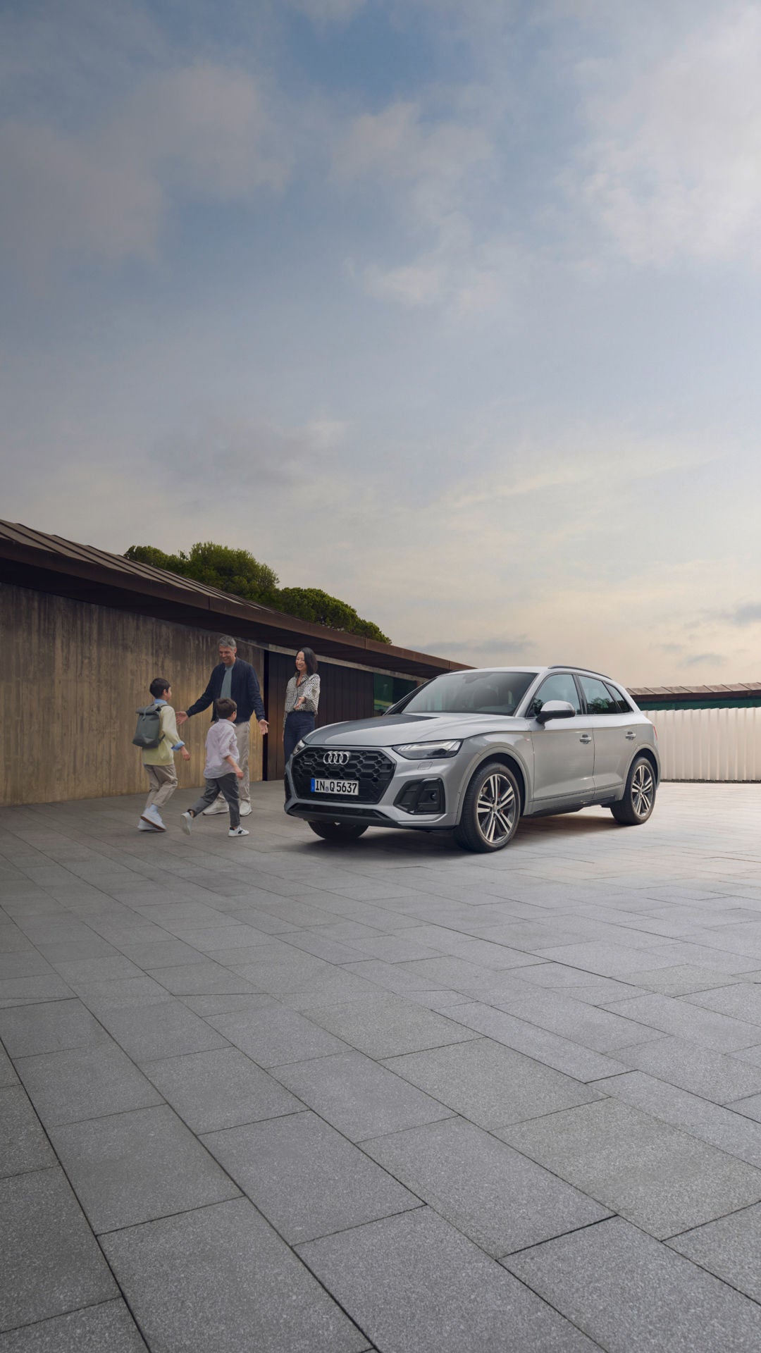 Family outside on a residential parking spot, next to an Audi SUV