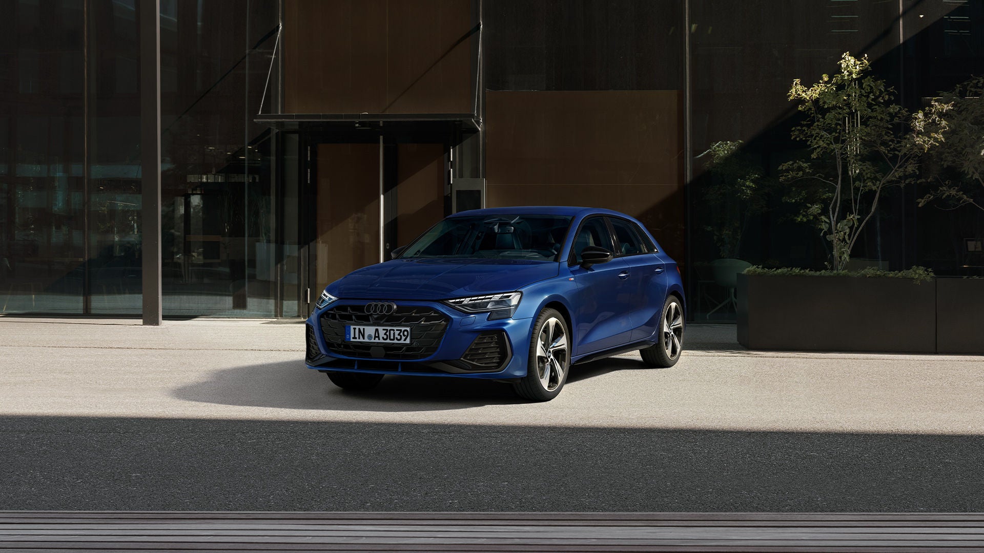 Une Audi A3 bleue garée devant un immeuble moderne.