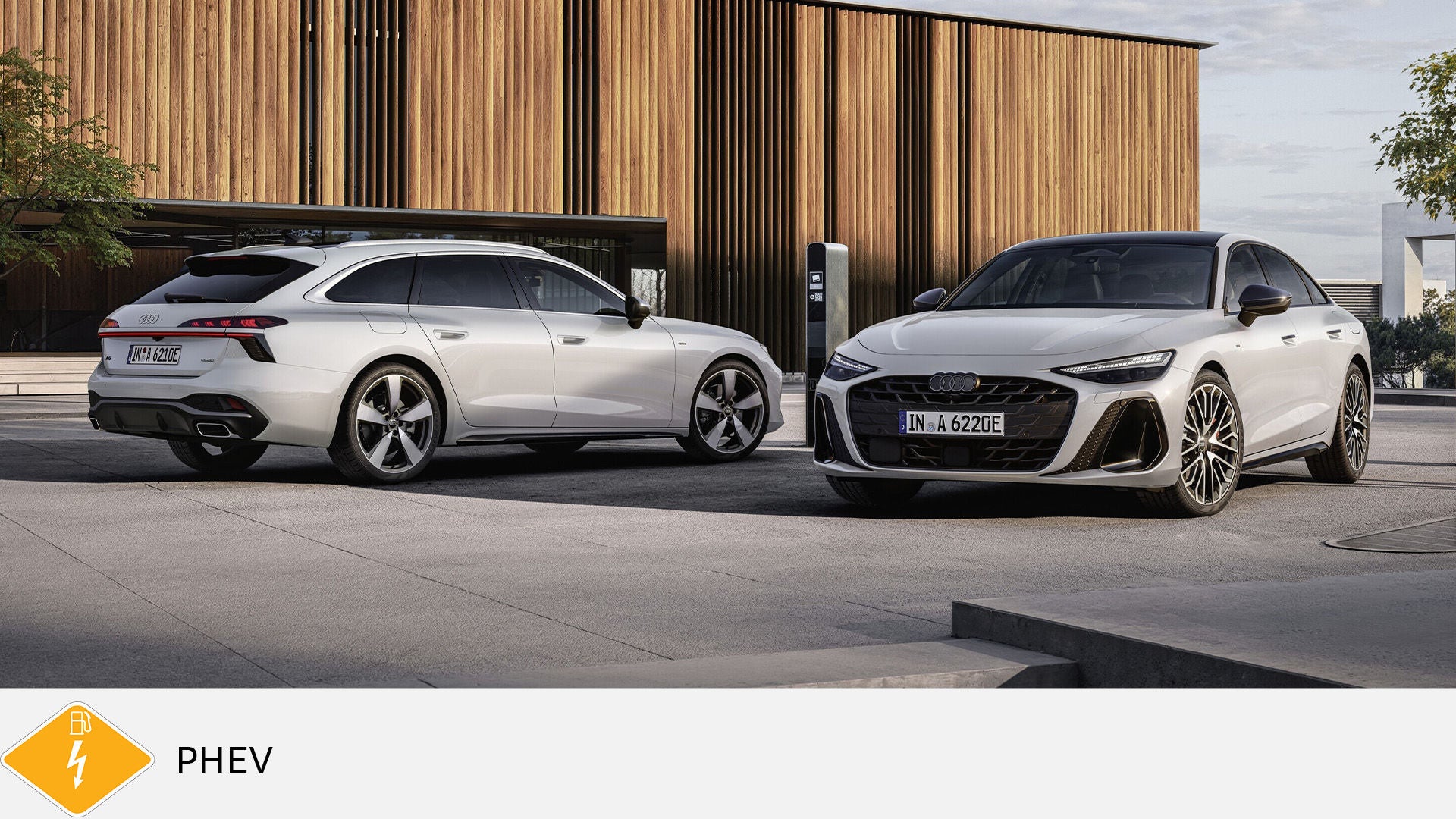 Two white Audi A6 plug-in hybrids in front of a modern wood facade, PHEV icon in bottom left corner.