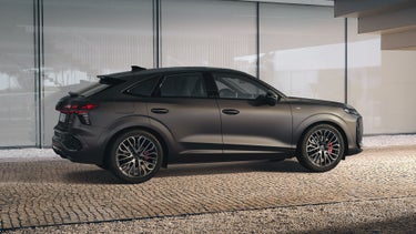 Der Q3 Sportback parkt vor dem Treppengeländer eines Gebäudes auf einem gepflasterten Weg.